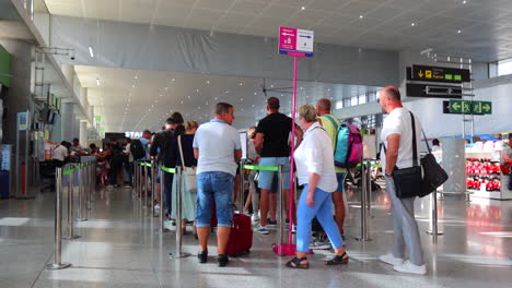 Menschen-Mit-Koffern-Warten-Am-Gate-In-Der-Schlange,-Um-Ein-Flugzeug-Am-Internationalen-Flughafen-Malaga-Zu-Besteigen,-Starbucks-Im-Hintergrund,-Urlaubszeit,-4K-Aufnahme