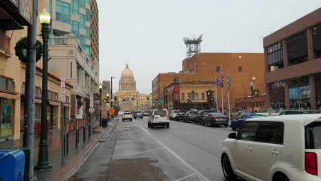 Scenic-street-view-with-snow-in-downtown-city-with-traffic-on-the-road-and-Idaho-State-Capitol-building-in-the-distance