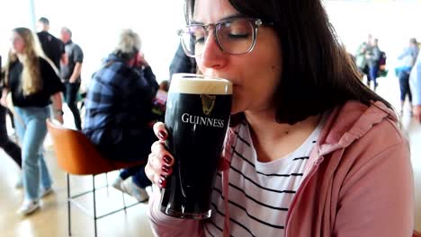 Cheerful-shy-girl-drinking-a-black-Guinness-beer-in-Dublin-brewery