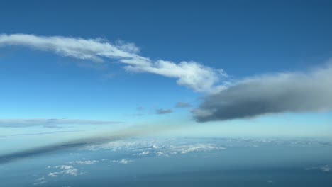 Die-Perspektive-Eines-Piloten,-Der-In-Einem-Blauen-Himmel-Mit-Einigen-Flauschigen-Wolken-Und-Seinen-Schatten-Fliegt