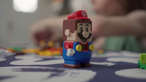 Nahaufnahme-Einer-Super-Mario-Legofigur,-Während-Ein-Junge-Ein-Super-Mario-Lego-Set-Baut