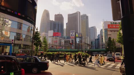 Slow-motion-establishing-shot-pan-of-busiest-city-in-Tokyo,-Shinjuku,-Warm-sunny-day-as-people-go-about-their-business