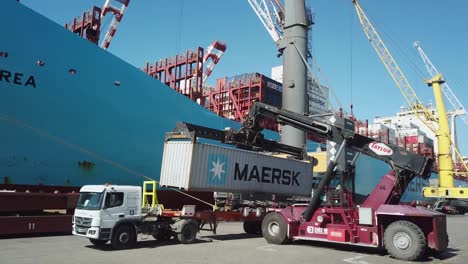 Truck-loading-a-container-at-a-busy-port-with-clear-skies,-crane-in-action-at-Port-of-Buenos-Aires