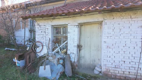 Whitewashed-brick-shed-with-a-red-slate-roof-and-a-wooden-door-with-some-junk-piled-up-in-front-of-it