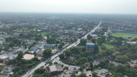 Zoom-out-drone-shot-of-Gujranwala-city-during-sunny-day-in-Punjab,-Pakistan-with-beautiful-cityscape-at-background