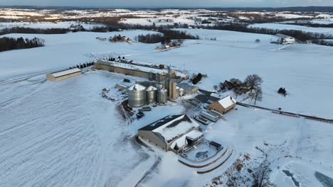 Wide-aerial-view-of-Midwest-grain-farm-and-bins-covered-in-winter-snow