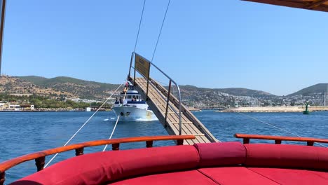 Wooden-stern-on-a-big-sailing-boat-in-Bodrum-Turkey-with-yachts-passing,-fun-summer-vacation,-the-rear-back-of-a-moving-boat,-luxury-holiday-destination,-sunny-sea-day-with-blue-sky,-4K-shot