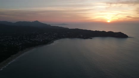 Aerial-pullback-establishes-Sayulita-Mexico,-stunning-coastal-getaway-town-with-epic-sunset