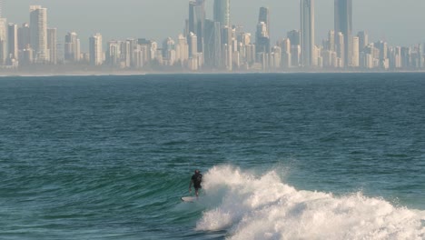 Surfistas-Disfrutando-De-Las-Olas-En-Un-Día-Soleado-Con-Surfers-Paradise-Al-Fondo,-Burleigh-Heads,-Gold-Coast,-Australia