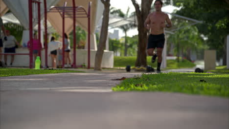 Zeitlupe-Eines-Hemdlosen-Lateinamerikanischen-Athleten,-Der-Seine-Laufroutine-In-Richtung-Der-Kamera-Im-Park-Beendet