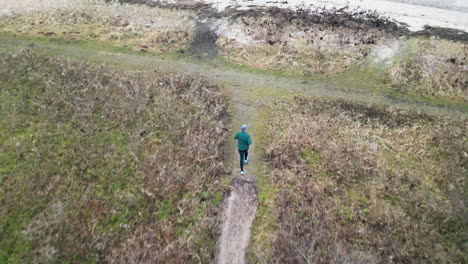 Aerial-view-of-runner-on-a-rural-path-in-early-morning-near-the-beach