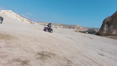 Tour-En-ATV-En-Capadocia:-Turistas-En-Quads-Conduciendo-Por-Terreno-árido-En-Capadocia,-Turquía-Con-Vistas-A-Las-Chimeneas-De-Hadas