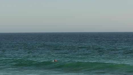 Surfer-waiting-for-waves-on-a-sunny-day,-Burleigh-Heads,-Gold-Coast,-Australia