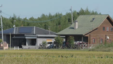 Rustikales-Holzhaus-Mit-Sonnenkollektoren-Inmitten-Von-Feldern-In-Kyushu,-Japan,-An-Einem-Sonnigen-Tag