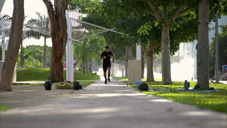 Slow-motion-of-a-latin-male-athlete-running-towards-the-camera-training-at-the-park