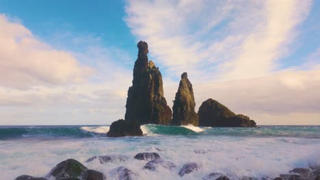 Slow-motion-shot-of-crashing-waves-on-rocky-beach-in-front-of-rock-formation-on-Madeira-Island