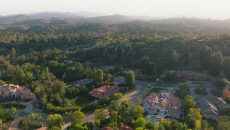 Flying-Over-Hidden-Hills,-Calabasas-at-Sunset,-Drone-Footage-of-Exclusive-Luxury-Neighborhood-with-Mountains-on-Horizon