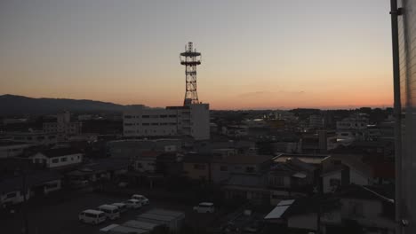 Dusk-settles-over-Izumi,-Japan-with-a-silhouette-of-a-communication-tower,-urban-landscape-bathed-in-twilight