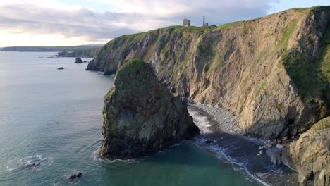 Drone-static-with-sea-stack-calm-seas-and-ruins-of-old-copper-mine-on-cliff-top