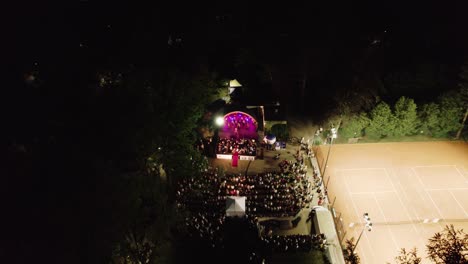 4K-Luftaufnahme-Eines-Live-Musikkonzerts-Auf-Beleuchteter-Bühne-Im-öffentlichen-Park-Bei-Nacht
