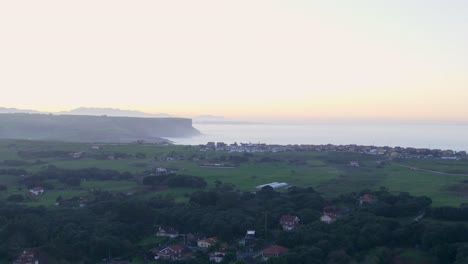 Sunset-Sea-of-Biscay-horizon,-Spanish-coastal-town-Playa-de-Isla-AERIAL