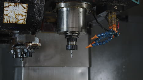 Close-up-of-a-CNC-machine-in-operation-with-cooling-fluid-spraying,-industrial-setting