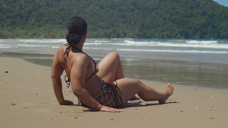 Enjoying-the-sun-and-sea,-a-bikini-fitness-model-embraces-a-day-of-leisure-on-a-Caribbean-beach