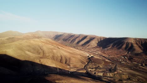 Fuerteventuras-Trockene-Landschaft-Mit-Kurvenreichen-Straßen-Bei-Sonnenuntergang,-Goldene-Stunde,-Luftaufnahme