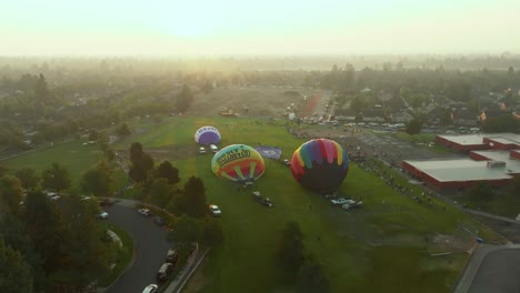 Wide-drone-shot-of-hot-air-balloons-inflating-at-the-Balloons-Over-Bend-event-in-Bend,-Oregon