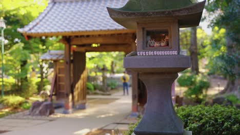 Slow-motion-pan-establishing-shot-of-temple-gates-and-stone-lantern-with-lucky-cats-at-Gotokuji