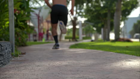Slow-motion-of-a-shirtless-man-running-sprinting-away-from-the-camera-getting-progressively-out-of-focus