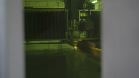 Industrielle-CNC-Maschine,-Die-Metall-Mit-Funken-Schneidet,-Durch-Einen-Spalt-Betrachtet