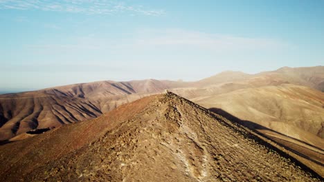 Karge,-Hügelige-Hügel-Unter-Klarem-Himmel-Auf-Der-Insel-Fuerteventura,-Luftaufnahme