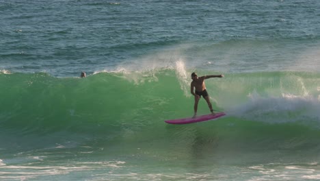 Surfer-on-a-longboard-catching-a-wave-on-a-sunny-day,-Burleigh-Heads,-Gold-Coast,-Australia