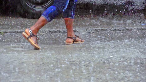 Close-up-of-legs-walking-through-huge-puddles-on-the-street-during-heavy-rain