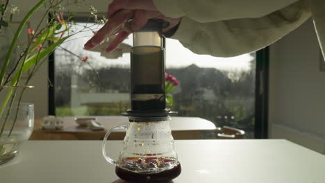 Pressing-down-a-coffee-maker-on-a-sunny-kitchen-table