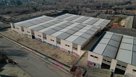 Large-industrial-warehouses-with-graffiti-near-Abrera,-Barcelona,-Spain,-aerial-view
