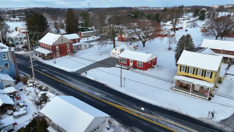 Yellow-red-and-brick-homes-along-quiet-road-in-rural-USA-covered-in-winter-snow