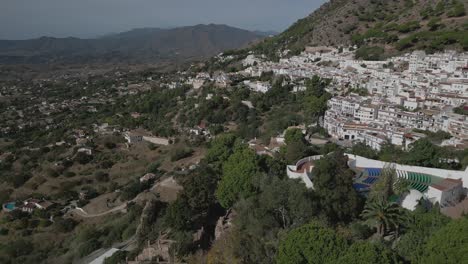 Mijas-village-with-white-buildings-nestled-on-hillside,-sunny-day,-aerial-view