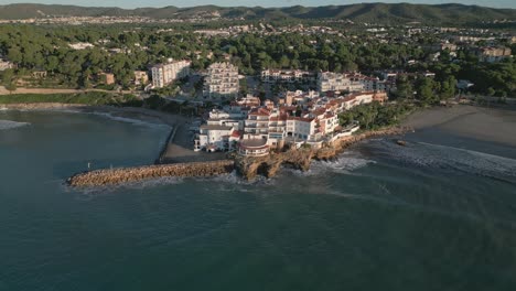 Roc-Sant-Gaietà-village-on-Costa-Dorada-during-sunrise,-calm-sea,-aerial-view