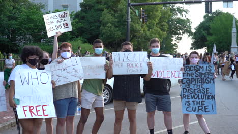 Group-of-young-adult-protesters-holding-black-lives-matter-signs-in-the-city-streets-with-masks-on-at-a-peaceful-protest