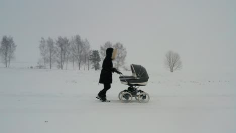 Mother-with-baby-carriage-walk-during-severe-winter-weather-with-snowfall
