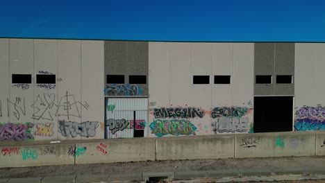 Mit-Graffiti-Bedeckte-Lagerhauswand-Unter-Blauem-Himmel,-Abrera,-Barcelona,-Spanien,-Urbane-Kunst,-Luftaufnahme
