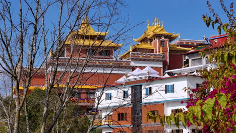 Drone-shot-of-Namobuddha-monastery-at-Dhulikhel-Nepal,-sunny-weather-beautiful-scenery-with-garden-flowers,-trees,-greenery,-colorful-vibe-peace-4K
