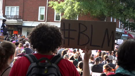 Activist-at-black-lives-matter-protest-holding-up-a-#blm-cardboard-sign-in-the-city-streets