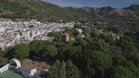 Mijas-village-in-Malaga,-Spain,-nestled-between-lush-hills-under-clear-skies,-aerial-view