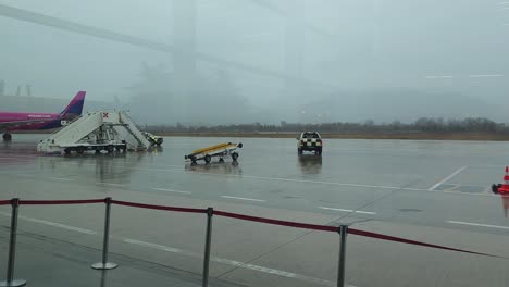 Flughafen-In-Rinas-Tirana,-Flugzeuge-Steigen-Ein,-Sicherheitsautos-Mit-Schwarzen-Und-Gelben-Streifen-Patrouillieren-Auf-Der-Landebahn