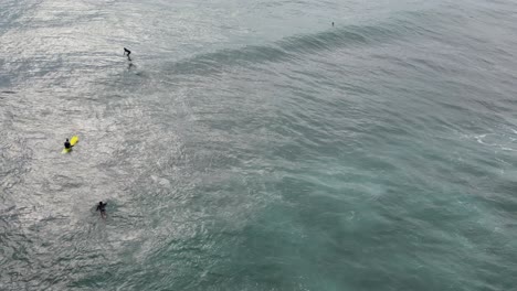 Aerial-drone-tracking-shot-captures-an-adventurous-man-hydrofoil-surfing-in-the-ocean-on-a-sunny-day,-exuding-the-thrill-and-joy-of-summer-wake-surfing