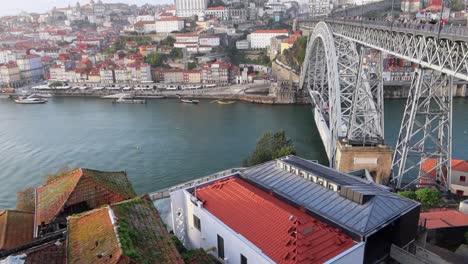 Tilt-up-shot-of-Porto-and-Luis-I-Bridge-with-people-crossing-River-Douro-by-day