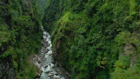 El-Dron-Viaja-Entre-Dos-Acantilados-De-Colinas-Verdes,-Un-Río-Que-Fluye,-Filmado-Como-FPV,-árboles,-Paisaje-De-Nepal,-Cinemático-4k